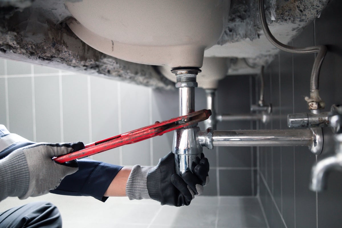 GTA plumber fixing water pipe under bathroom sink in Mississauga
